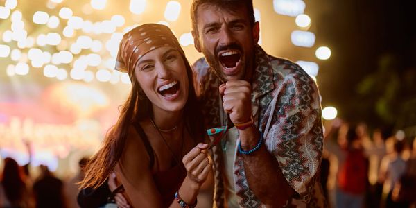 Joyful couple enjoying a festive night with bright lights in the background.