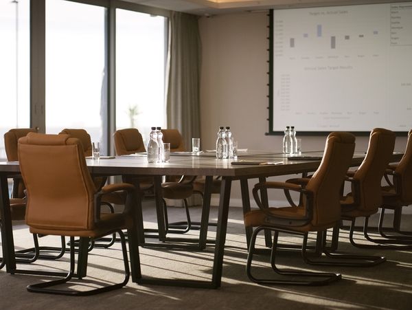 Empty conference room with brown chairs and a presentation screen.