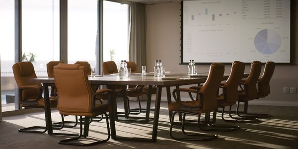 Empty conference room with brown chairs and a presentation screen.