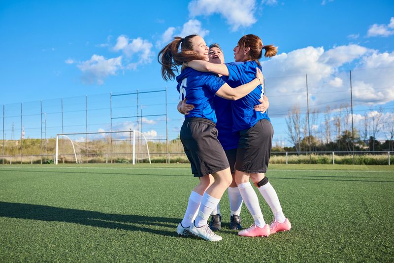 Soccer team members are embracing and rejoicing after scoring a goal.
