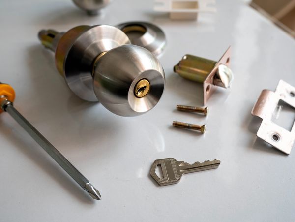 Disassembled door knob with key and screwdriver.