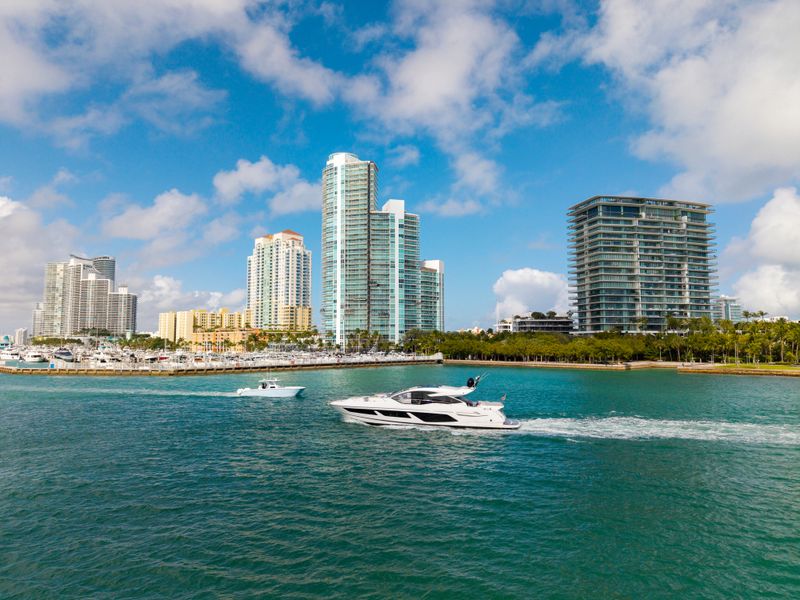 Luxury yacht cruising near Miami skyline. Aerial view of boats on turquoise waters in Miami. Yacht retreat in South Florida Miami. Miami cityscape with sailing vessels. Waterfront Miamis panorama