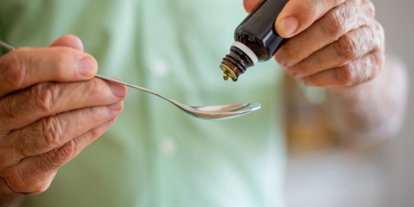 Person pouring medicine onto a spoon.