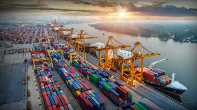 A busy shipping port with colorful containers and cranes at sunset.