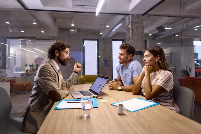 Mature bank manager talking to his customers during a meeting in modern office.