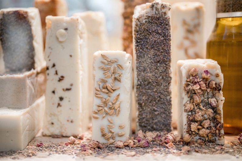 Natural handcrafted soap bars with dried herbs, flowers, and essential oils displayed in Al Balad soap shop, highlighting artisanal craftsmanship and organic beauty care. A close-up of intricate textures and earthy colors emphasizes their authenticity.