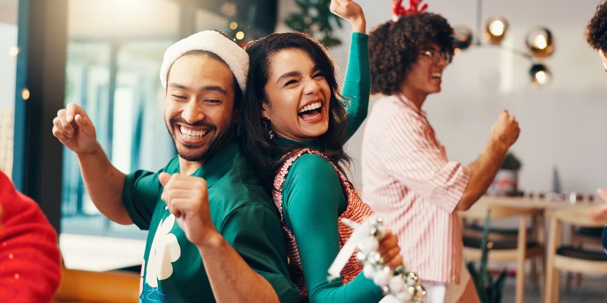 Friends joyfully dancing and celebrating indoors during a festive holiday party.