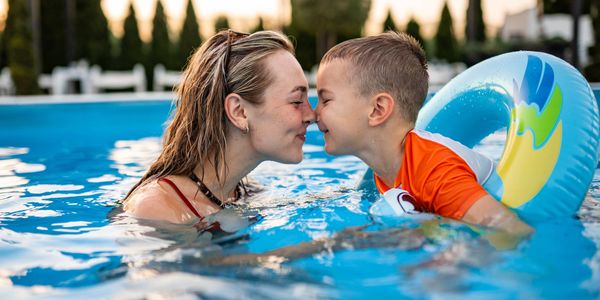 Mother and son sharing a loving moment in the pool with noses touching.
