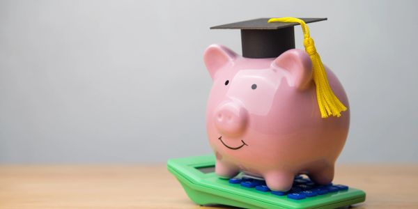 Piggy bank with graduation cap on calculator.