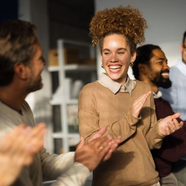 People clapping and smiling in a cheerful indoor setting.