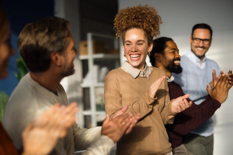 Group of happy multi-ethnic businesspeople clapping hands during a meeting in the office, celebrating success