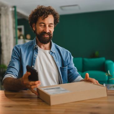Man happily receiving a package while holding a phone.