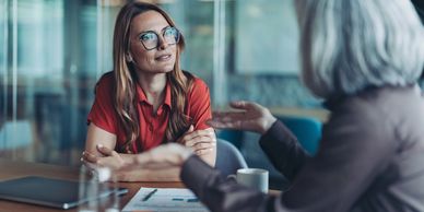 Two women engaged in a thoughtful office conversation.