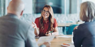 A woman smiling and talking in a meeting.