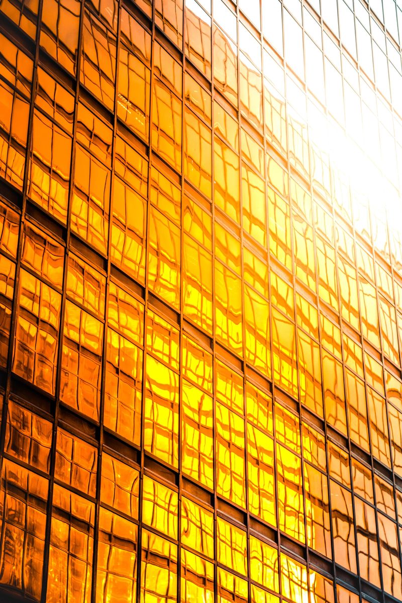 Warm sunlight reflecting on a modern glass building facade, creating golden hues