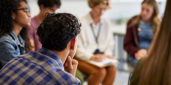 Group in discussion with man in plaid shirt focused.