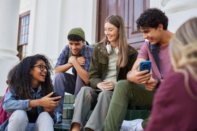 Group of diverse young friends chatting and laughing on steps.