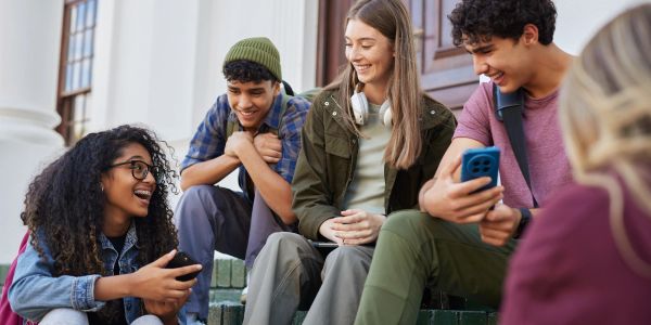 Group of diverse teenagers hanging out and smiling outdoors.