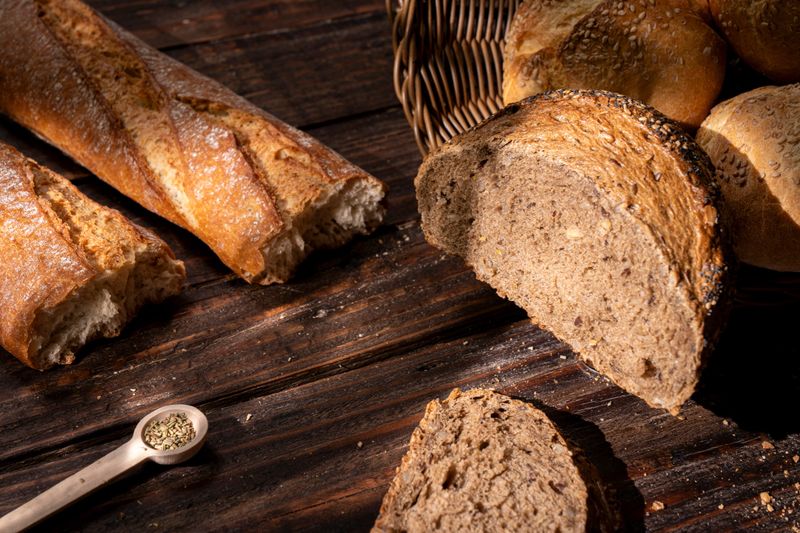 Assortment of artisan bread on rustic wooden table, including baguette and wholegrain loaf. Concept of fresh, healthy bakery, organic ingredients and homemade traditional food.