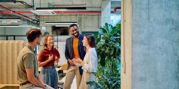 Four colleagues chatting and smiling in a modern office.