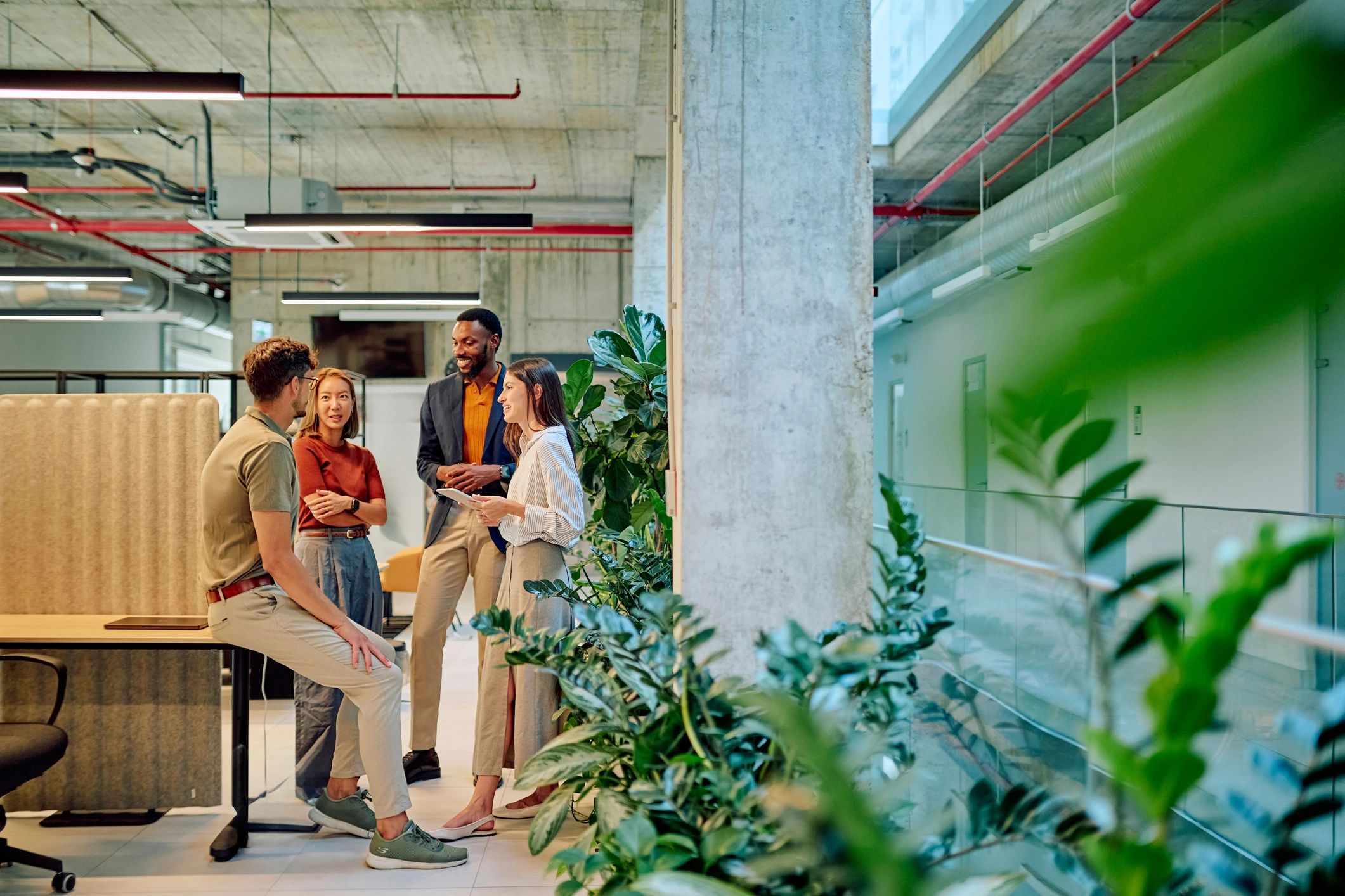 Four colleagues chatting happily in a modern office.