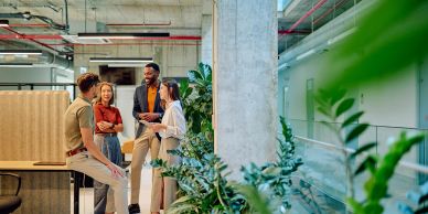 Four colleagues chatting happily in a modern office.