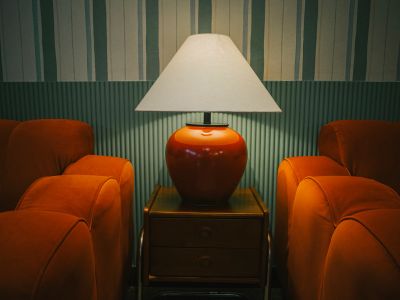 Orange lamp on table between two orange armchairs.
