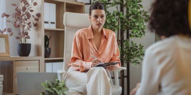 Woman in peach blouse conducting an interview.