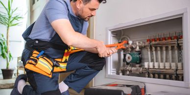 Plumber fixing pipes with wrench indoors.