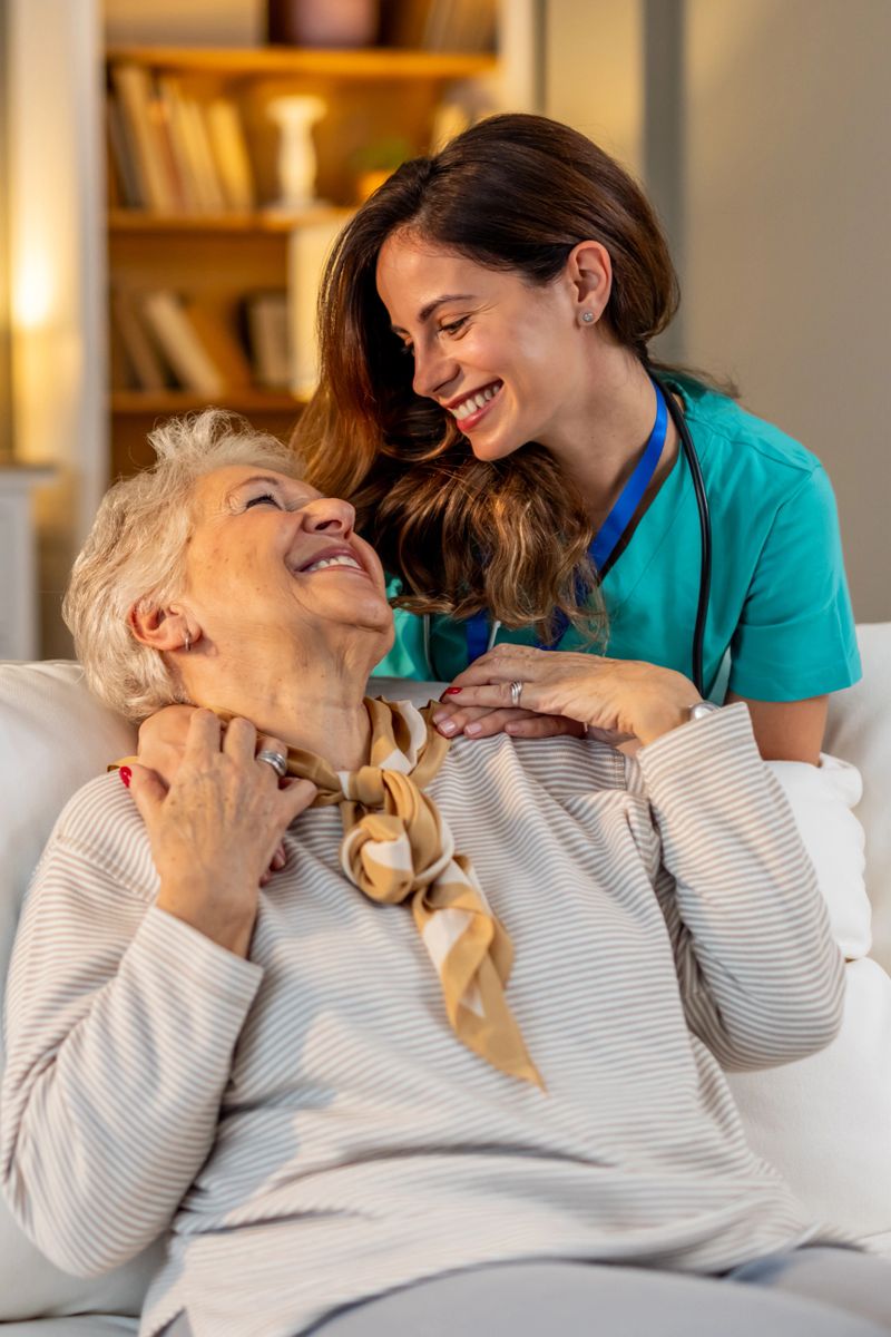A loving caregiver and elderly woman share a heartfelt and cheerful interaction in a cozy home setting, showcasing compassion, support, and genuine connection.