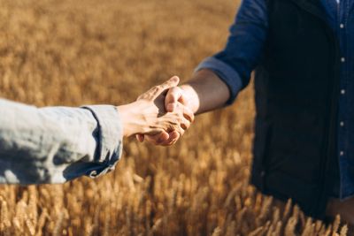 Due persone si tengono per mano in un campo di grano.
