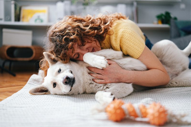 A woman enjoying quality time with her dog, showing affection while lying in a comfortable home environment. The scene captures a moment of warmth, companionship, and love between a person and her pet.