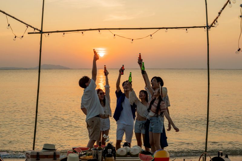 Group of Asian people with friends party on the beach. Lifestyle on summer holiday.
