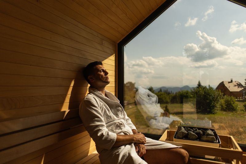 Man relaxing in sauna with a view on sky and beautiful green nature