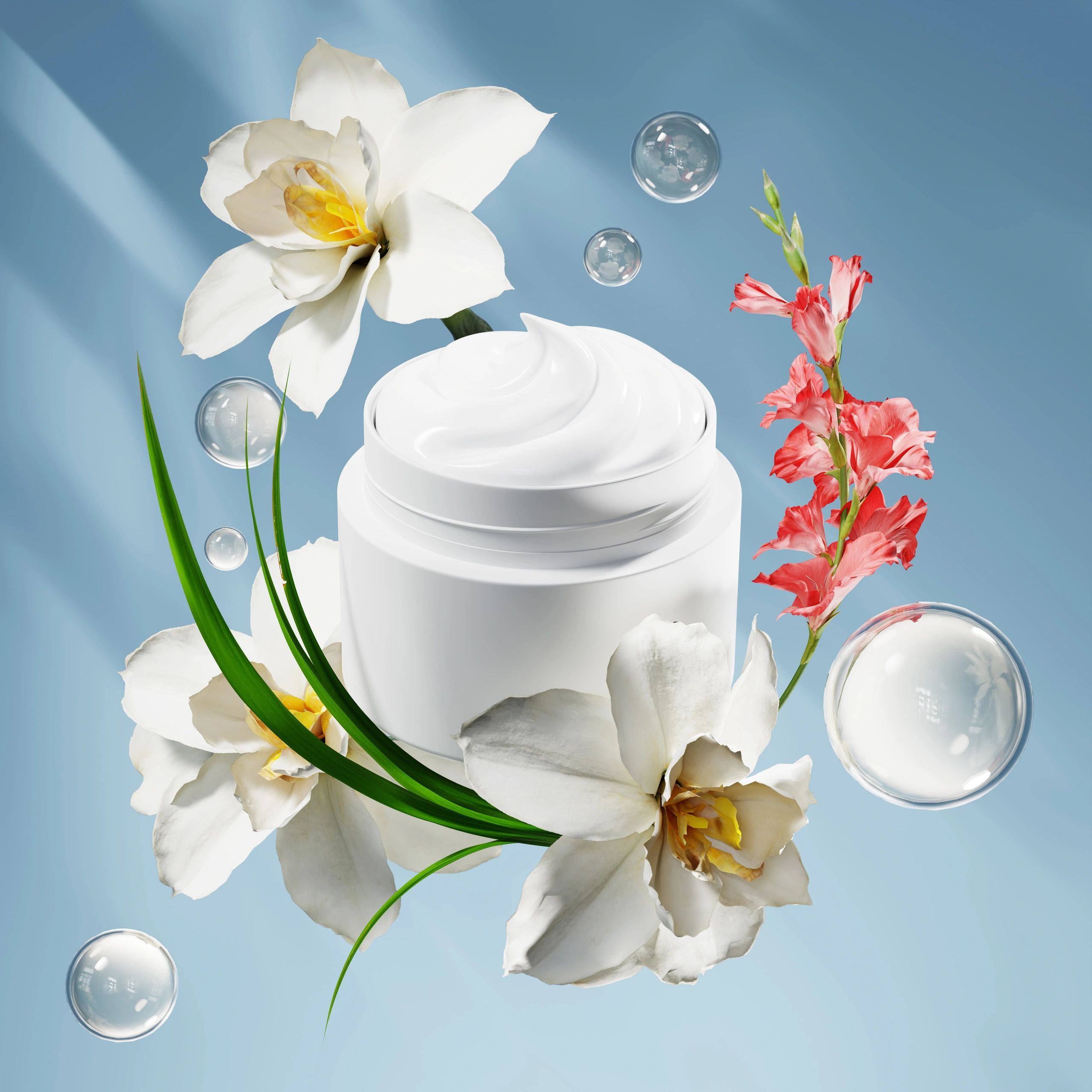 A jar of white cream surrounded by white and pink flowers with bubbles against a blue background.
