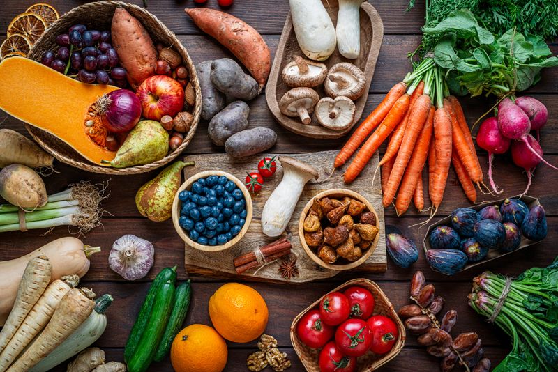 Healthy Autumnal fruits and vegetables on kitchen table. Fresh organic seasonal produce background. Healthy vegetarian raw food. Food that boost the body inmune system. Overhead view