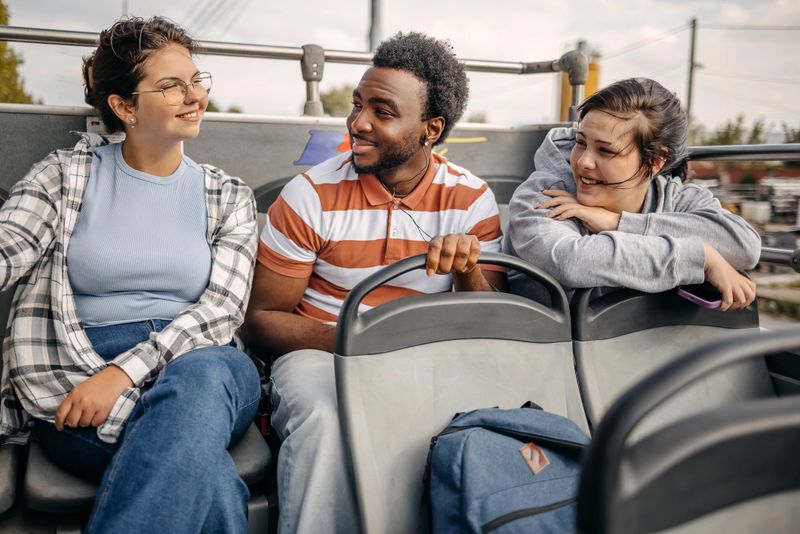 Group of friends enjoying open roof bus tour together and smiling