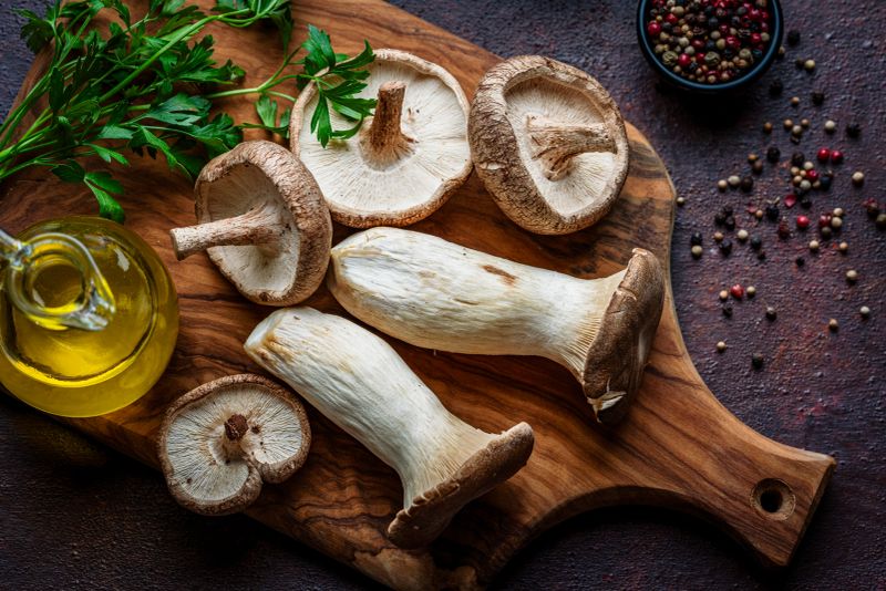 Pleurotus eryngii. King trumpet mushroom or king oyster mushroom on wooden cutting board. Cooking or preparing vegetable meal. Umami flavor