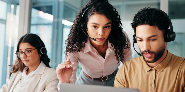Three call center agents working with headsets in an office.