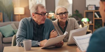 Elderly couple reviewing documents with a professional at home.