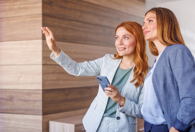 Two businesswomen using a smartphone app for augmented reality visualization of a property