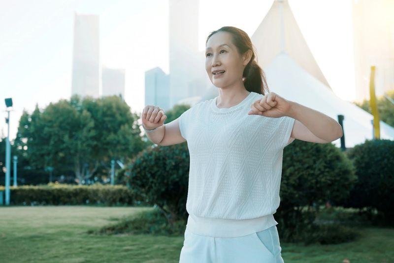 Middle-aged Asian Woman Practicing Tai Chi in Park