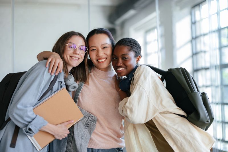 Diverse teenagers expressing joy as they bond in a well-lit, academic setting, showcasing friendship, diversity, and education.