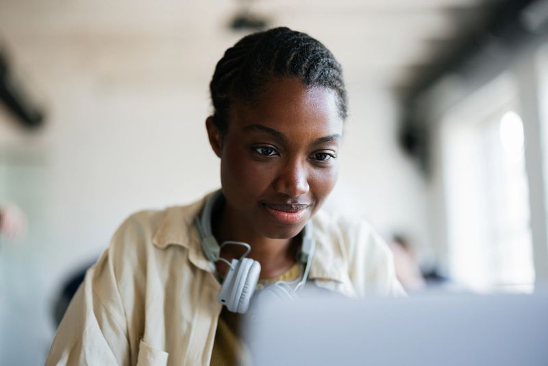 Confident young woman immersed in her studies at a contemporary learning environment, wearing headphones.