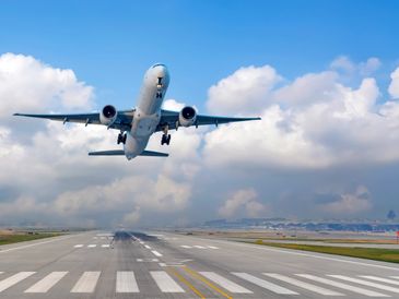 Commercial airplane taking off from runway under a partly cloudy sky.