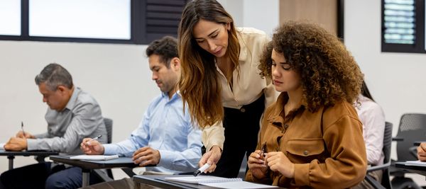 Teacher helping student in classroom.