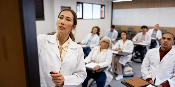Female instructor teaching medical students in a classroom.
