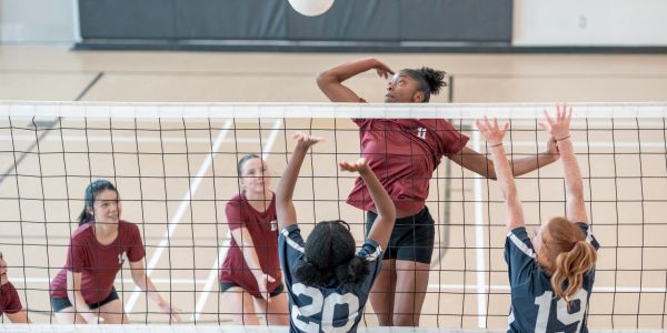 Volleyball player jumps to spike the ball over the net.