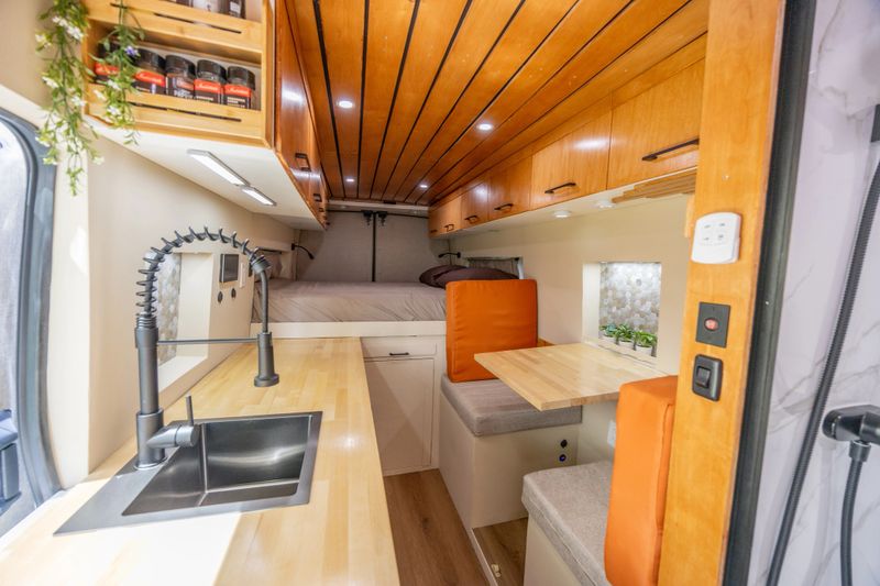 Interior view of an RV with a warm and cozy design, featuring wooden accents and soft lighting for a homely atmosphere.