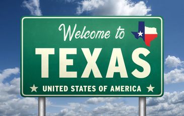 Black pickup truck displayed on a ramp with American flags.